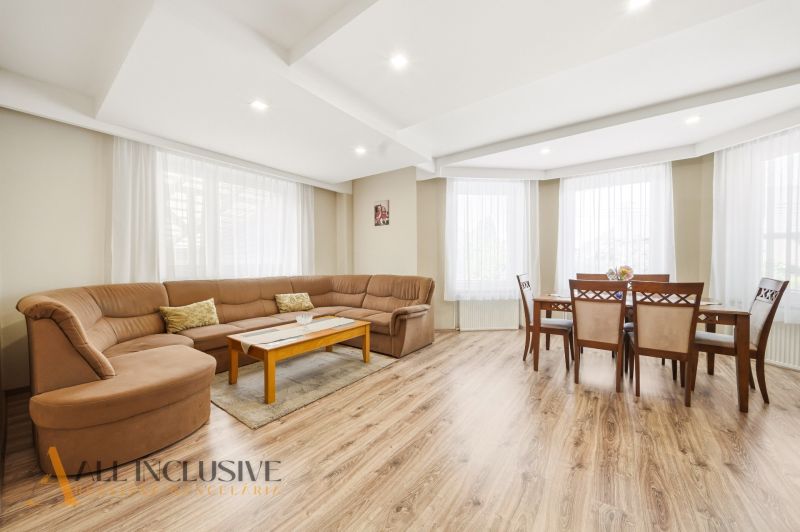Living room with a large sofa, dining table, and floor with a wooden decor.