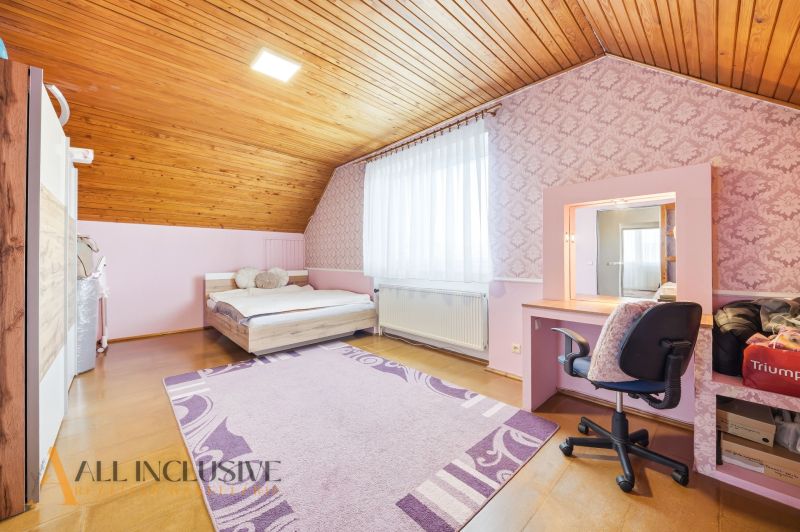 Attic room in a family house with a wooden decor floor and pink walls.