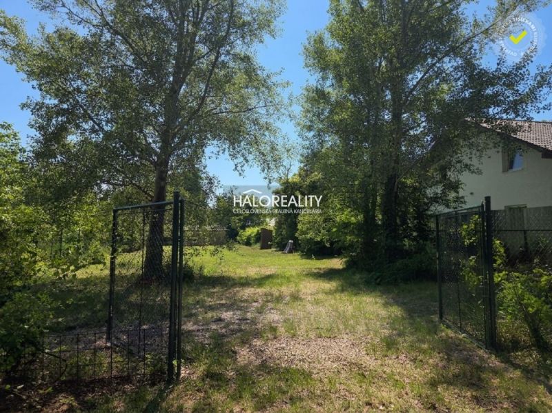 Land - residential in Potônské Lúky, fenced area with lawn and trees.