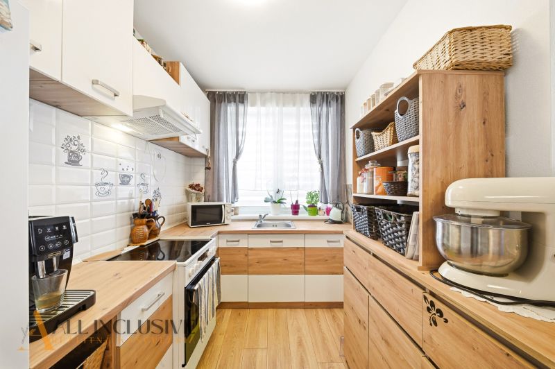 A kitchen with appliances and shelves in a 3-room apartment with a wooden decor floor.