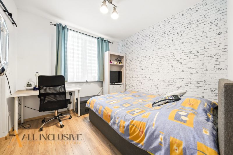 A bedroom with a desk, chair, brick wallpaper, and a wooden decor floor in a 3-room apartment.