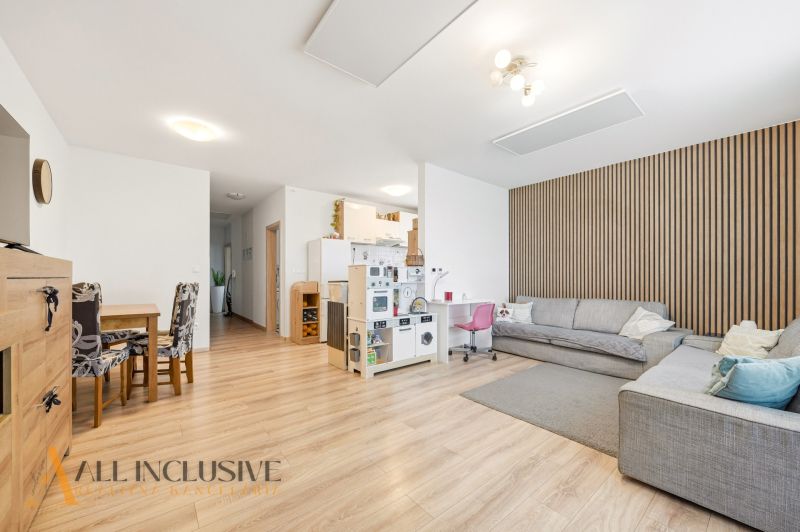 Living room with wood-patterned flooring in a 3-room apartment, gray sofa, dining table.