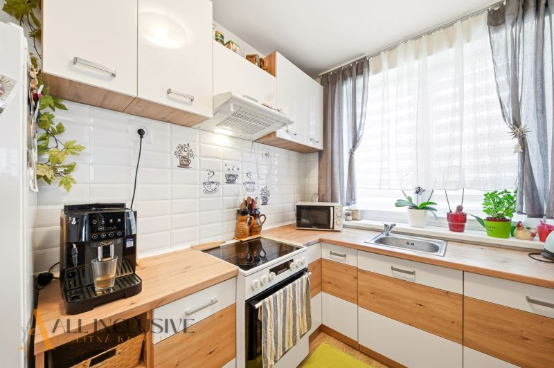 A kitchen with appliances, curtains, and a wooden decor floor in a 3-room apartment.