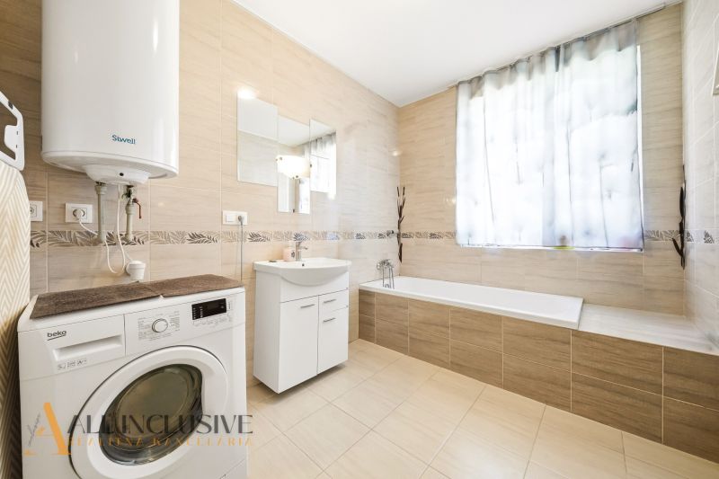 A spacious bathroom with a bathtub and a washing machine in a 3-room apartment.