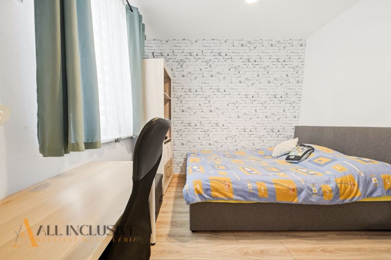 Bedroom in a 3-room apartment with a wooden decor floor, a table, and a bed.