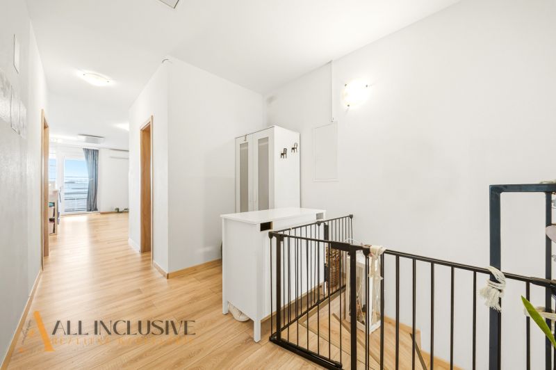 A hallway in a 3-room apartment with white furniture and a wooden decor floor.