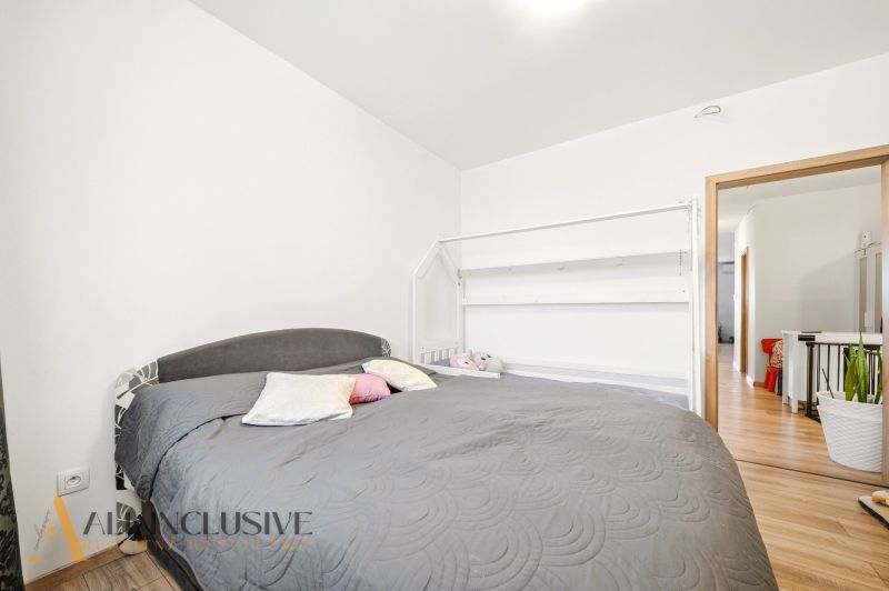A bedroom in a 3-room apartment with a large bed and a floor with a wood decor.