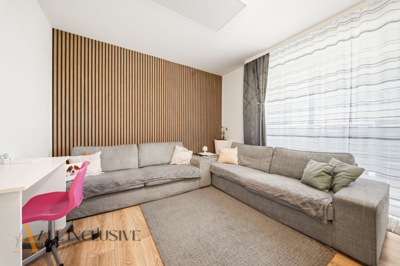 Living room in a three-room apartment with wooden decor and a gray sofa.