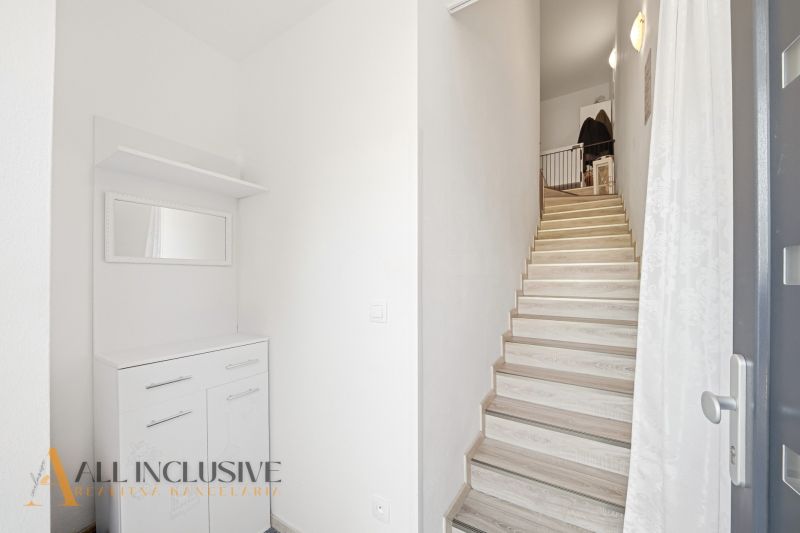 A hallway in a 3-room apartment with storage space and a staircase.