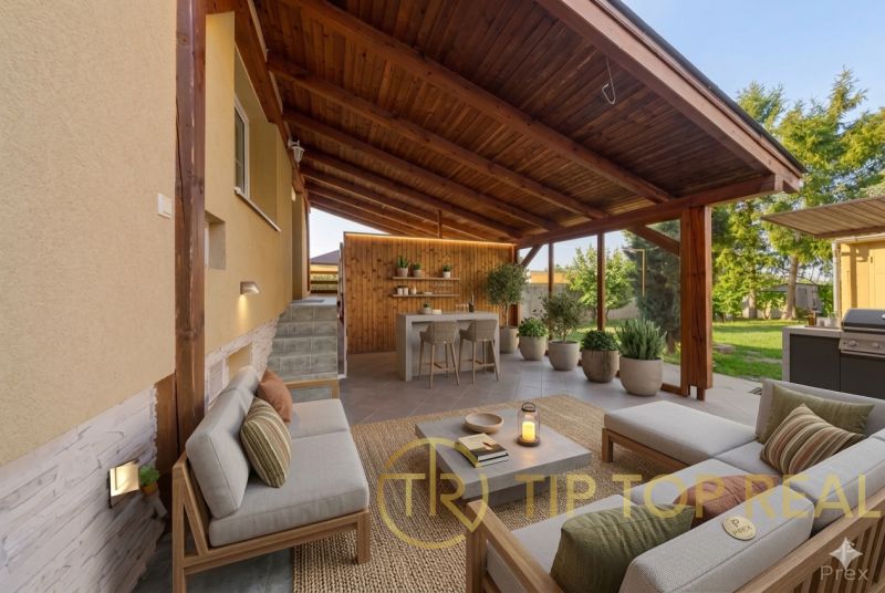 The terrace of a family house in Báč with wooden paneling, seating, and garden plants.