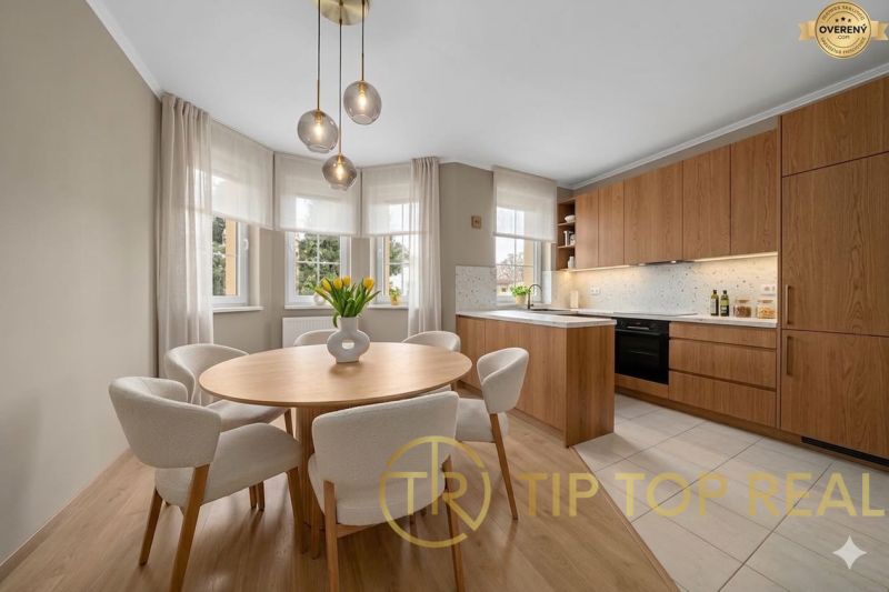 A kitchen in a family house with a wooden decor floor, a round table, and pendant lights.