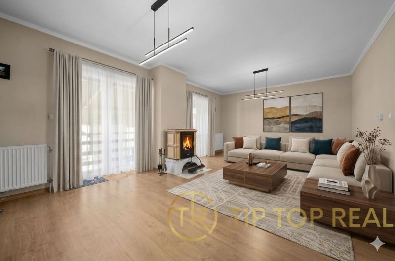 Living room in a family house with a wooden decor floor, a fireplace, and a corner sofa.