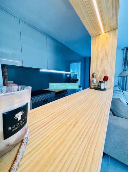 A kitchen unit in a 3-room apartment with a wooden decor floor and modern lighting.