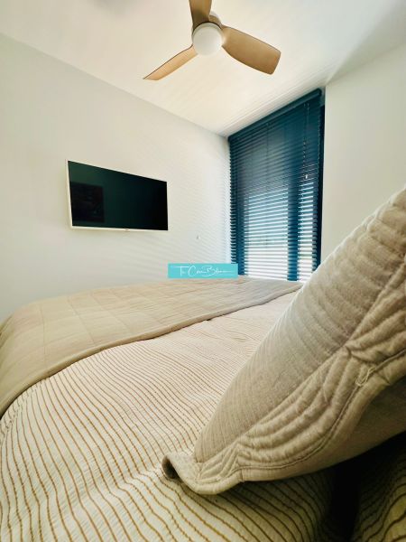 A bedroom in a 3-room apartment with a fan, television, and blinds for comfort.