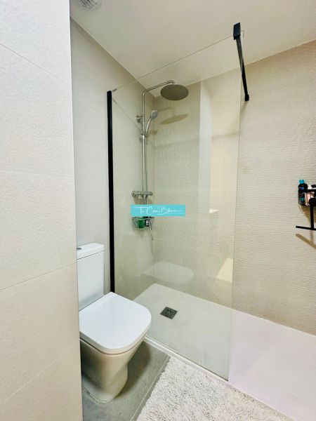 Shower corner with a toilet in the bathroom of a 3-room apartment, light tiles.
