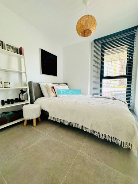 Bedroom in a 3-room apartment with a bed, white shelf, and window with blinds.