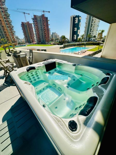 Hot tub on the terrace of a 3-bedroom apartment in Calpe, overlooking the pool and high-rise buildings.