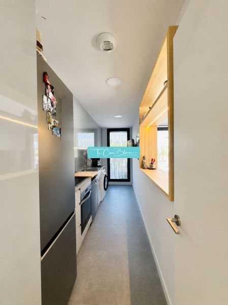 A narrow kitchen in a 3-room apartment with modern equipment and a gray floor.