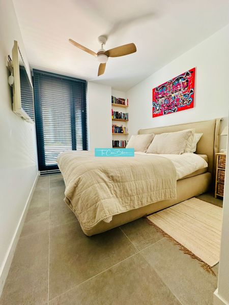 Bedroom in a 3-room apartment with a fan, bed, and art on the wall.