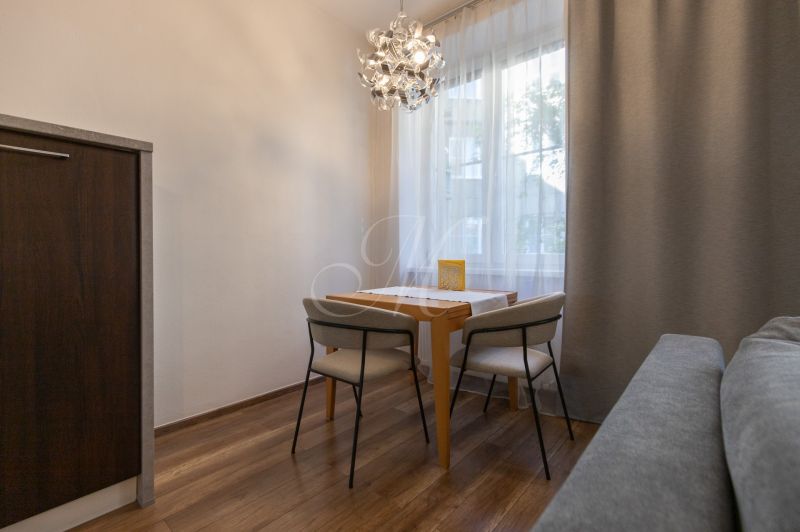Dining area with a table and two chairs, wooden decor flooring, pendant light.