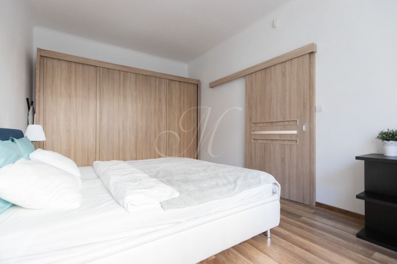 Bedroom in a 2-room apartment with a bed and wardrobes, floor with wooden decor.