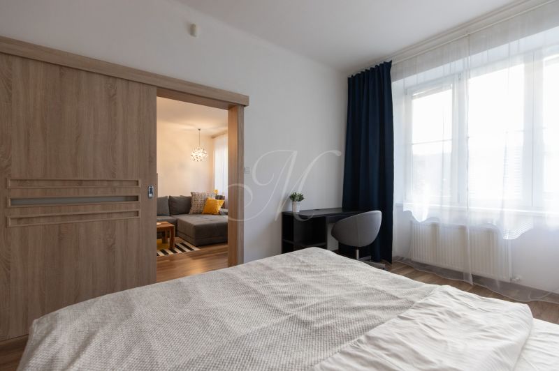 Bedroom with glass doors in a 2-room apartment, work desk, wooden decor flooring.