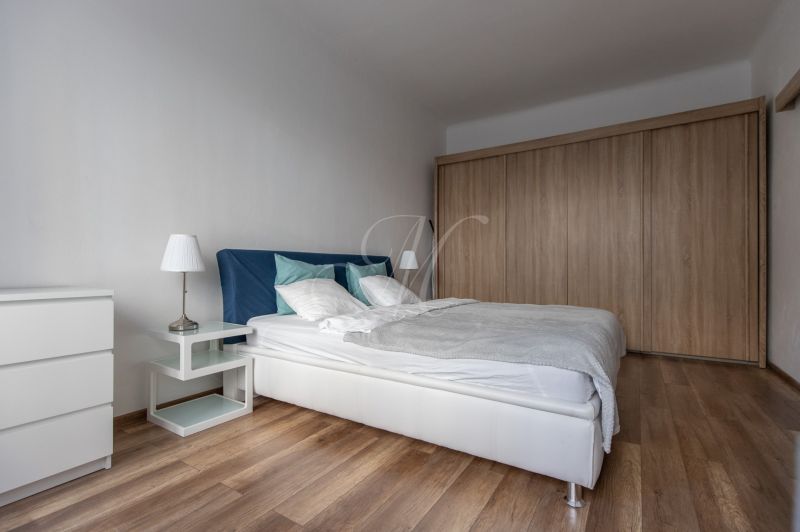 Bedroom in a 2-room apartment with a bed, built-in wardrobe, and wooden decor flooring.