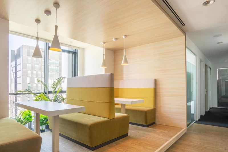 Dining in an office with a wooden floor decor and a view of a tall building.