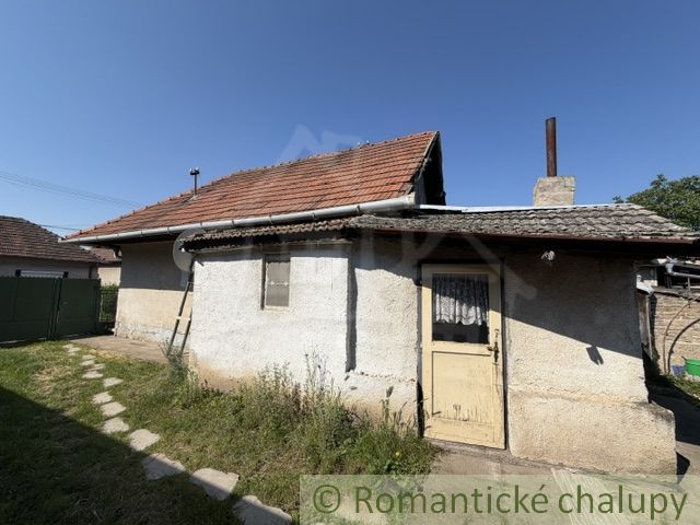 A family house in Šurany with a gable roof and a window, surrounded by a lawn.