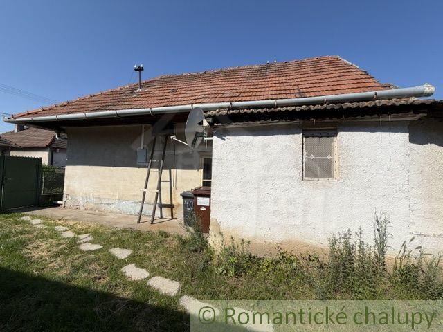 A family house in Šurany with a red roof, satellite dish, and garden.