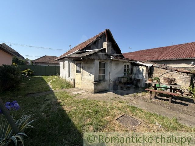 A courtyard of a family house in Šurany with a smaller older house and a table for sitting.