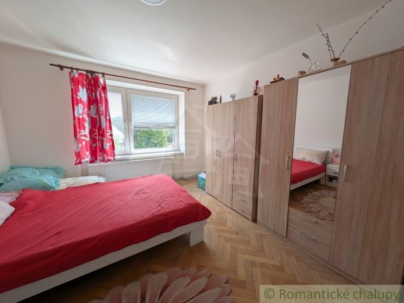 A bedroom with red bedding, a wardrobe, and a wooden decor floor in a two-room apartment.
