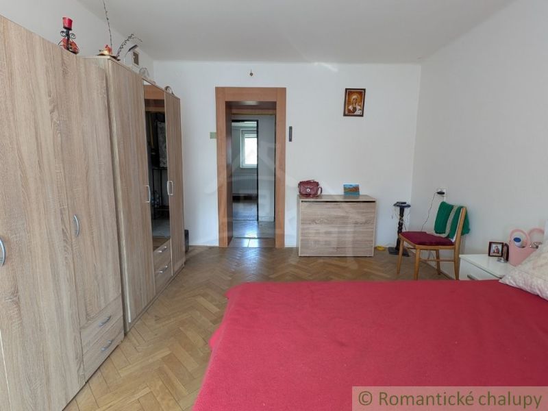 A room in a 2-room apartment with a bed, a floor with a wooden decor, and a wardrobe.