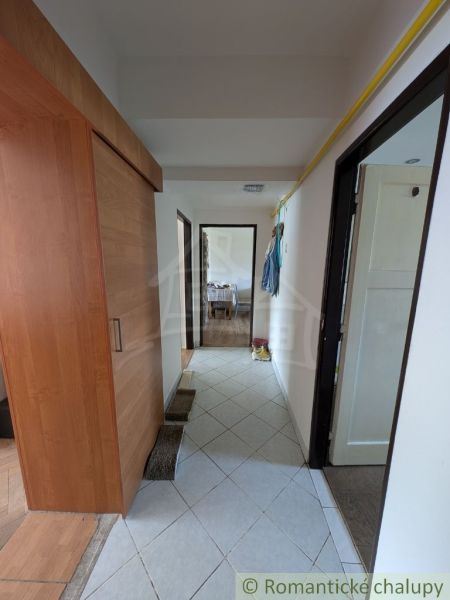 A hallway in a 2-room apartment with tiles and a floor cabinet with a wooden decor.