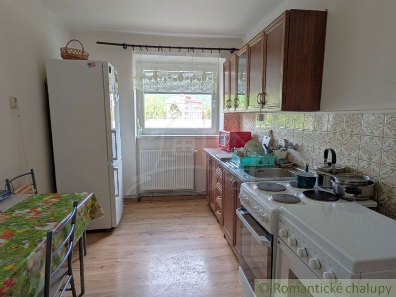 A kitchen in a 2-room apartment with ceramic tiles and a wooden decor floor.