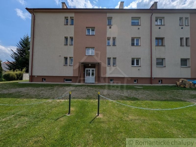 An apartment building in Medzilaborce with a green courtyard, three stories, and bright facades.