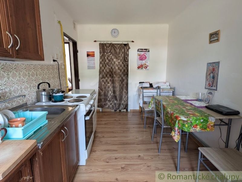 A kitchen in a 2-room apartment with a stove, sink, and a floor with a wooden decor.