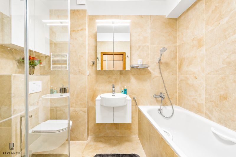 A bathroom in a 4-room apartment with a bathtub, shower, and beige tiles.