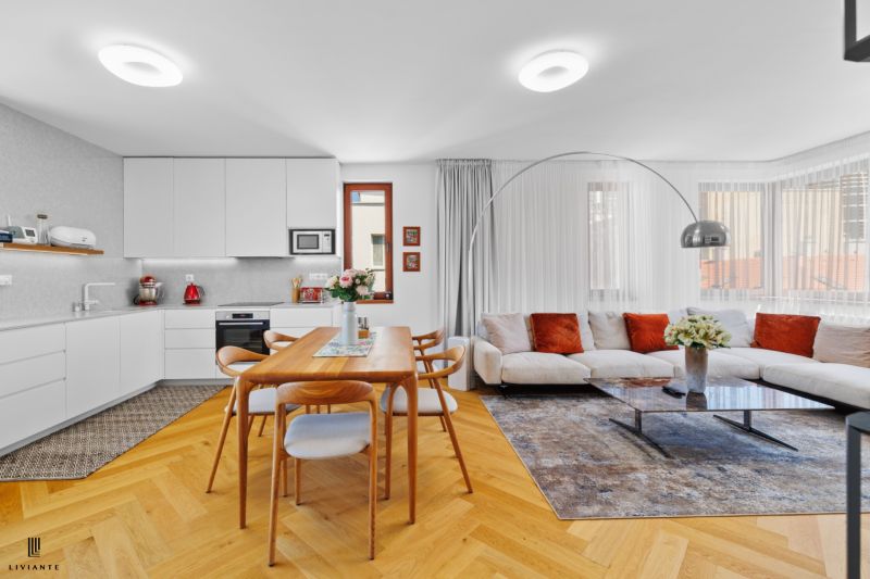 Bright kitchen and living room in a 4-room apartment with a wooden decor floor and a comfortable couch.