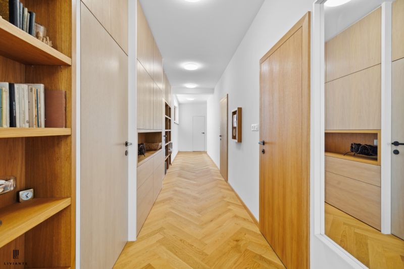 A hallway with a wood-patterned floor and built-in wardrobes in a 4-room apartment.