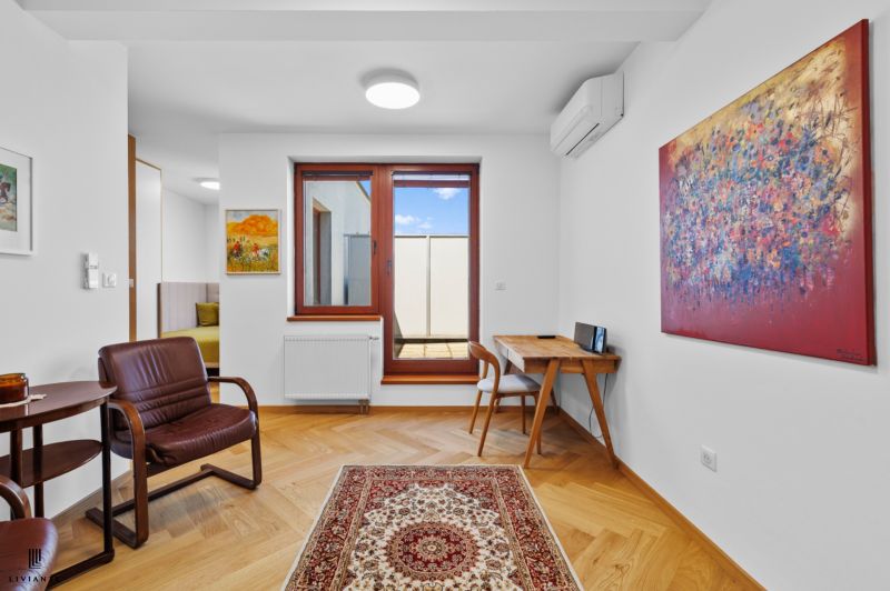 A living room with a chair, paintings, and a wooden decor floor in a 4-room apartment.