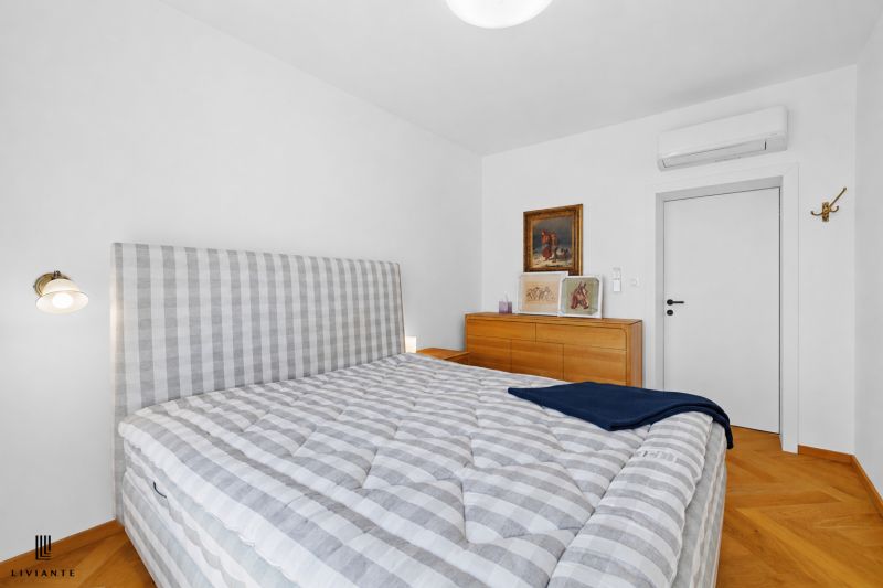 Bedroom with a patterned bed, paintings, and a dresser in a 4-room apartment, floor with wooden decor.