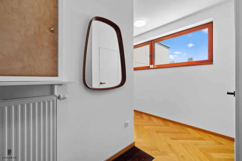Mirror, radiator, and window in a 4-room apartment with a wooden decor floor.