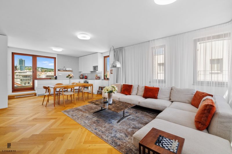 Living room in a 4-room apartment with a wooden decor floor, a large sofa, and a dining table.