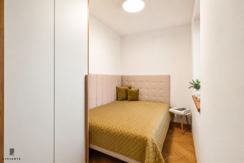Bedroom in a 4-room apartment with a bed, pillows, and a table, floor with wooden decor.