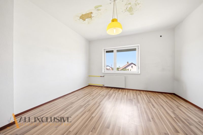 Empty room, wooden decor floor, damaged ceiling, yellow light fixture, window to the garden.