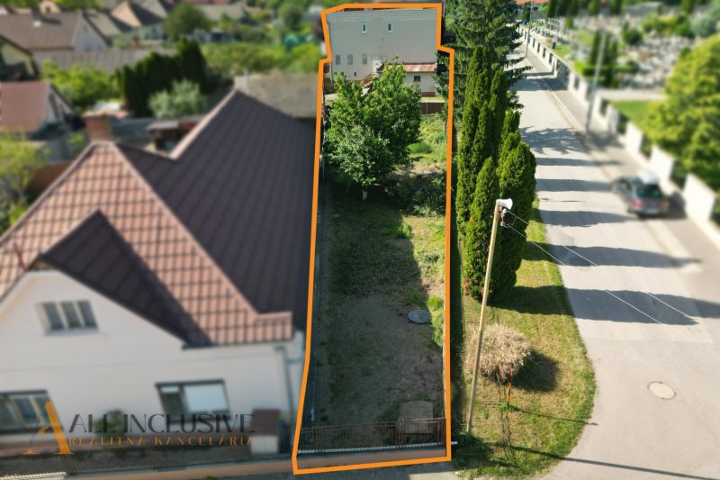A plot of land in Topoľníky next to a family house with trees and a road.