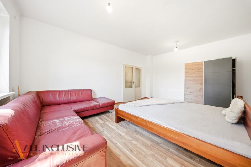 A room in a family house with a wooden decor floor and a red sofa.