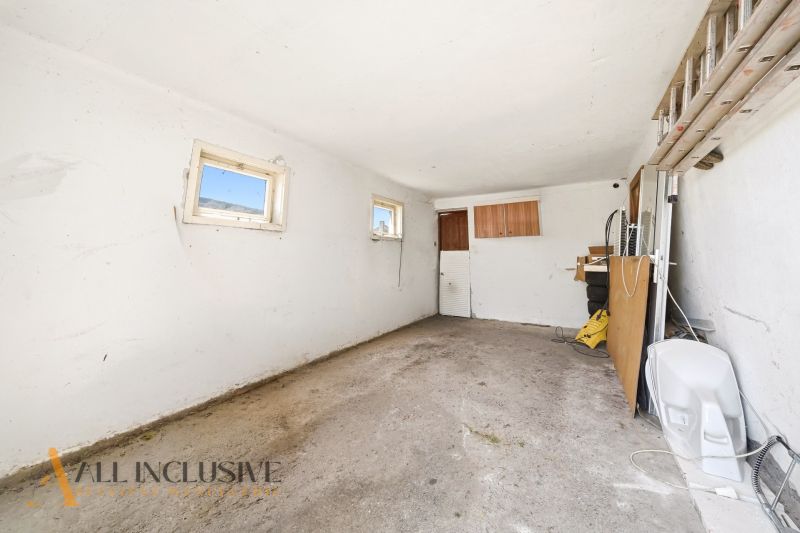 A spacious garage in a family house with white walls and small windows.