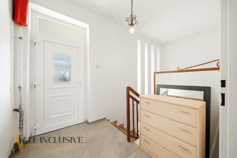 A hallway in a family house with white walls, doors, and a cabinet.